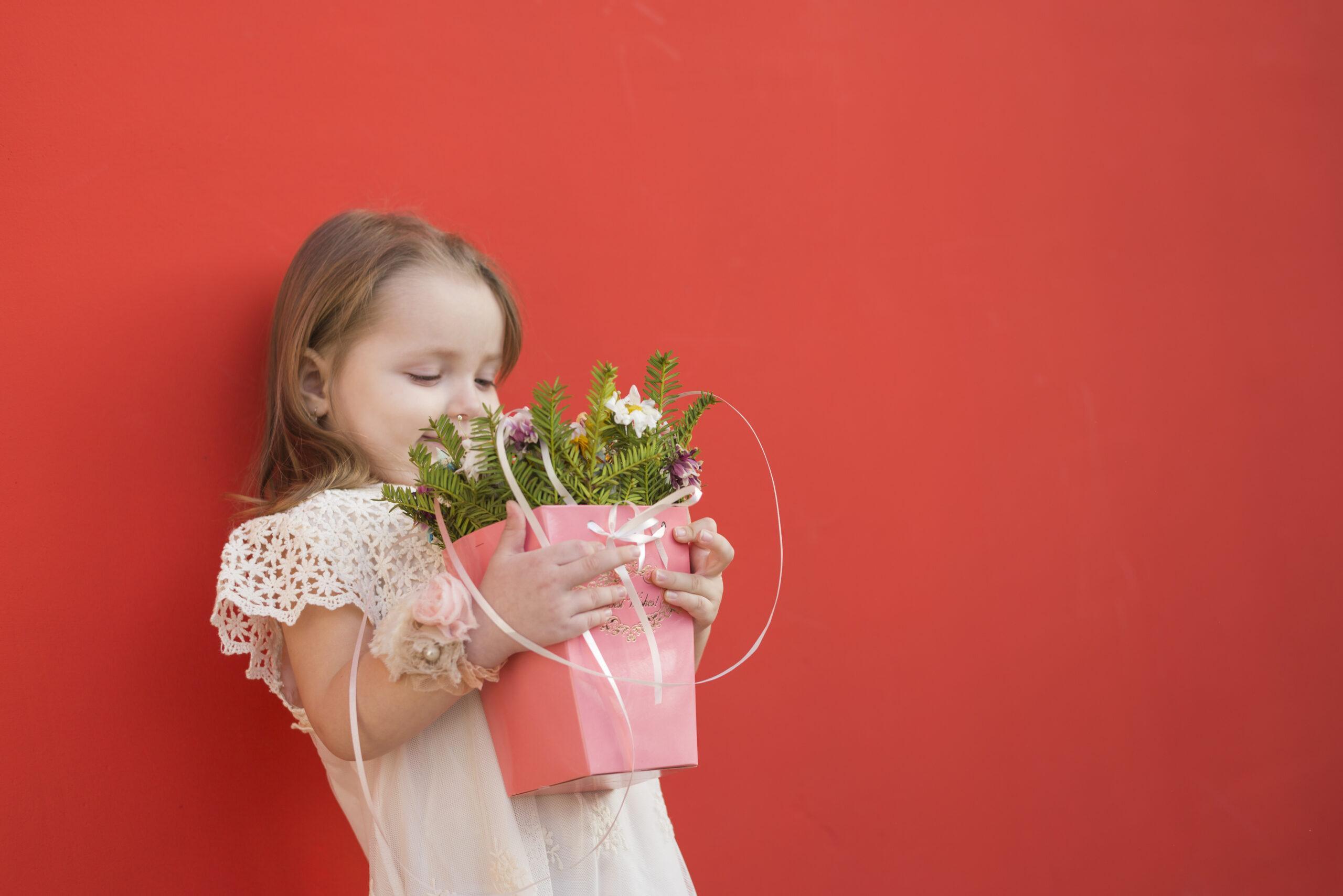 Petite fille tenant un pot fleuri , un cadeau fait main pour la Fête des Mère