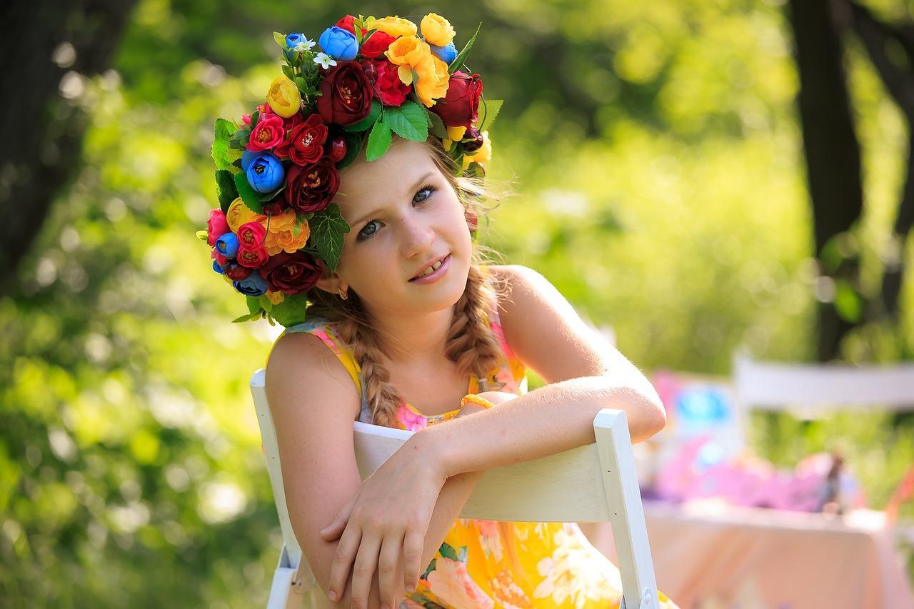 Petite fille souriante portant une couronne florale colorée sur la tête, prête à célébrer le carnaval.