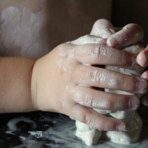 Les mains d'un enfant en train de modeler de l'argile, découvrant une activité créative et sensorielle.