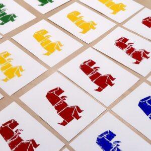 Plusieurs impressions sérigraphiées sur le thème dinosaures, disposées sur une table après un atelier pour enfants.