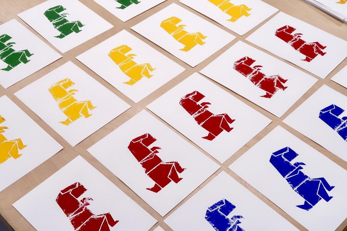 Plusieurs impressions sérigraphiées sur le thème dinosaures, disposées sur une table après un atelier pour enfants.