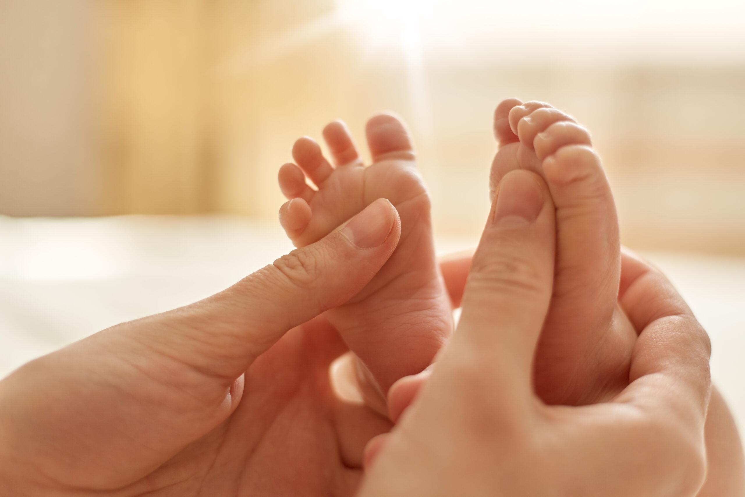 Pieds de bébé massés délicatement, mettant en valeur un moment de détente et de connexion entre le parent et l'enfant.