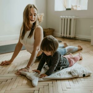 Parent et enfant pratiquant une posture de yoga ensemble sur un tapis, renforçant leur lien et favorisant la détente.