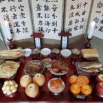 Table avec pleins d'aliments et un paravent avec de la calligraphie coréenne juste derrière