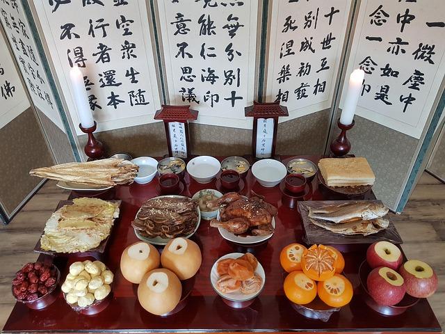 Table avec pleins d'aliments et un paravent avec de la calligraphie coréenne juste derrière