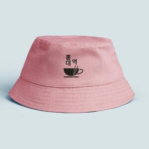 Bob de couleur rose sur fond gris, élément graphique du logo en noir qui est au milieu du bob