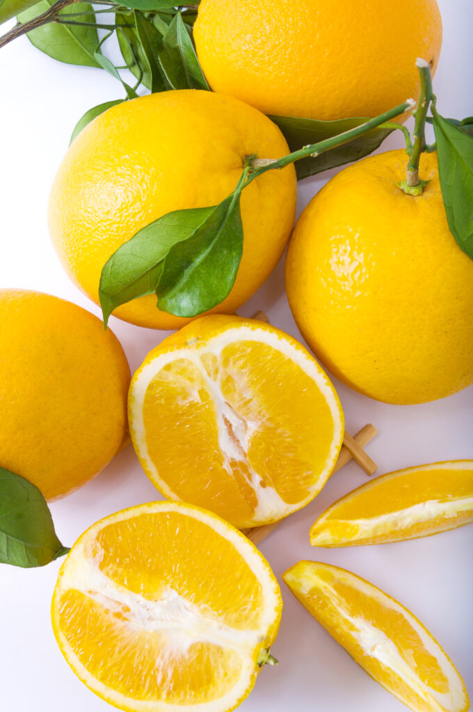 Yuzu coupé en tranche avec d'autres yuzu entier avec des feuilles poser juste à coté