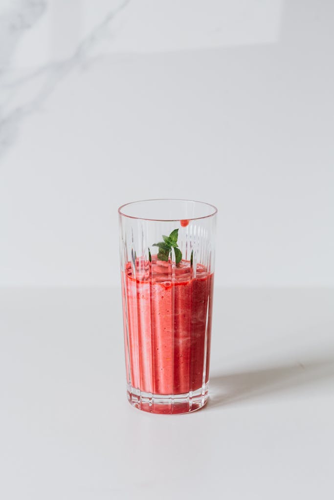 A refreshing strawberry smoothie in a glass with a mint garnish, ideal for a healthy lifestyle.