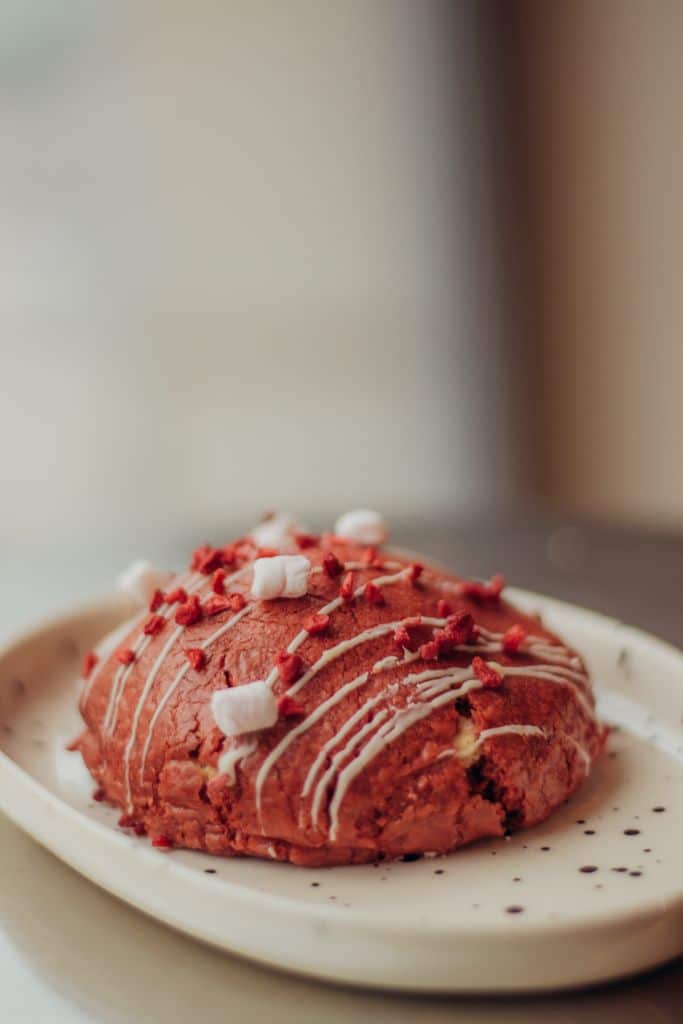 Close-up of a red velvet cookie with icing on a plate, perfect for dessert lovers.