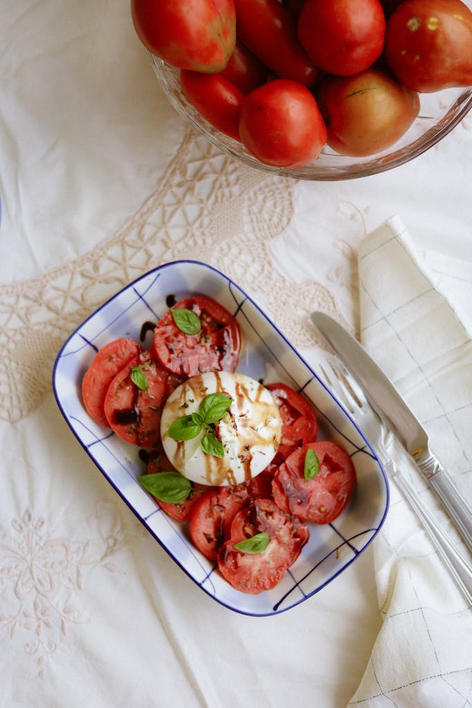 Delicious Caprese salad with fresh mozzarella, tomatoes, and basil on a white tablecloth.