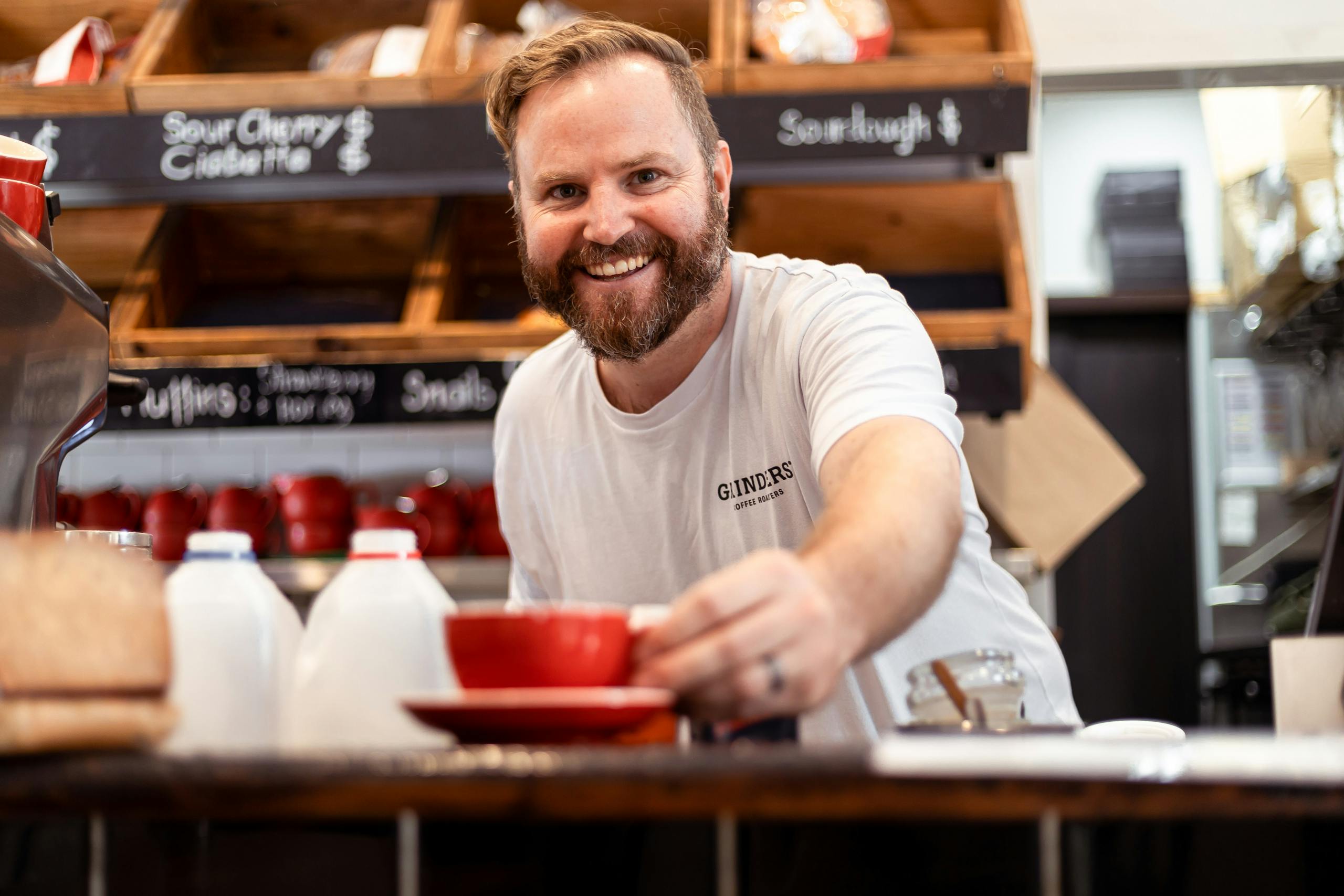 Barista tendant une tasse de café en souriant