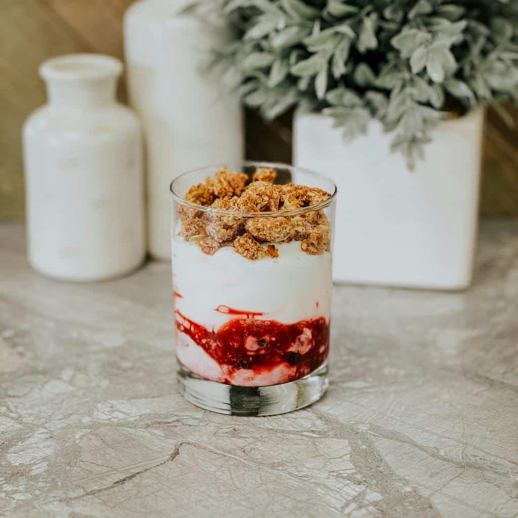 Indulgent berry parfait with creamy yogurt and crunchy granola in a modern still life setting.