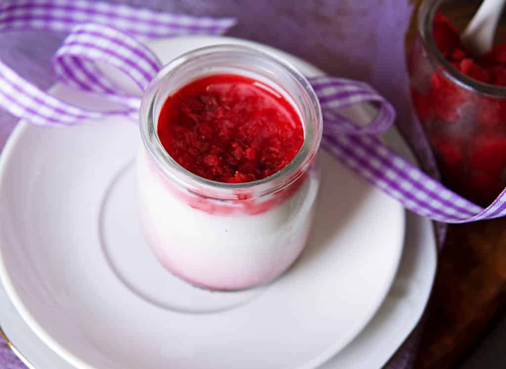 Tasty panna cotta dessert in a jar topped with fresh raspberries, perfect for a sweet treat.