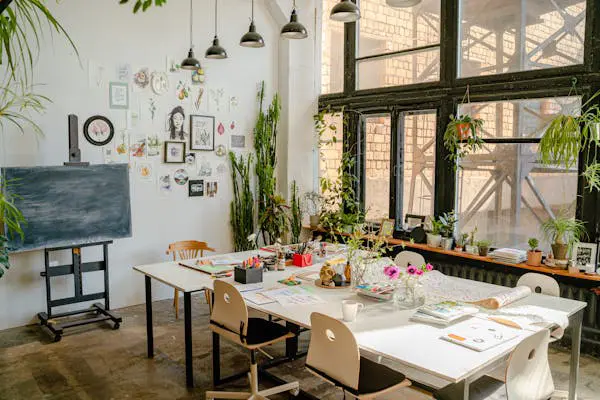 Atelier créatif lumineux avec tables, plantes et divers matériels créatifs