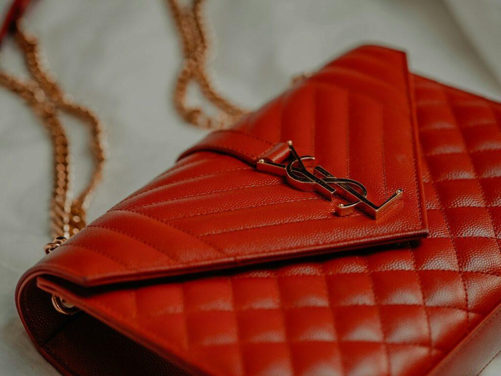 sac à main de la marque YSL, avec chaine en or, logo sur broche sur sac rouge