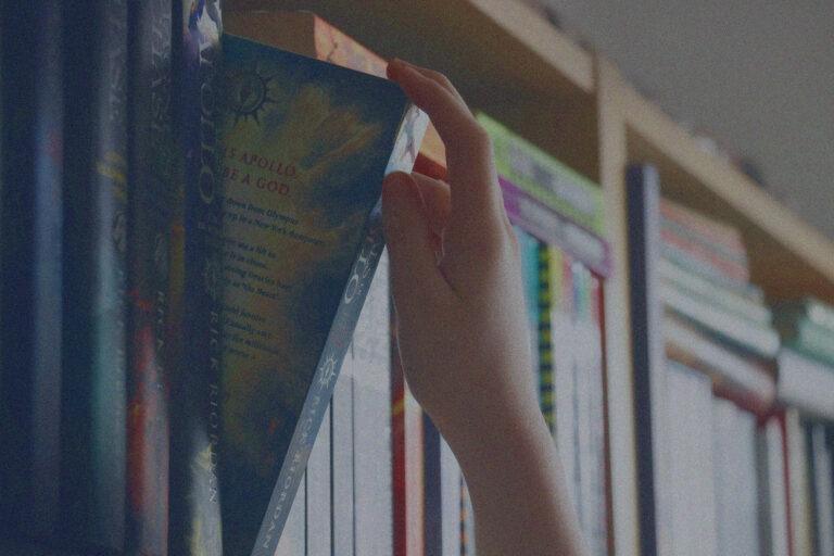 une personne qui prend un livre dans une bibliothèque.