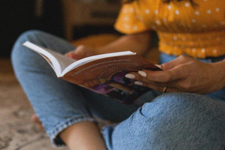 Une personne qui lit un livre assis en tailleur.